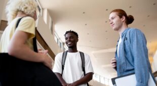 Photo représentant 2 étudiants et une étudiante en train de discuter au sein d'un établissement scolaire.
