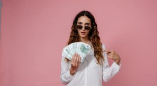 Femme portant des lunettes de soleil, tenant des billets d'euros, sur un fond rose