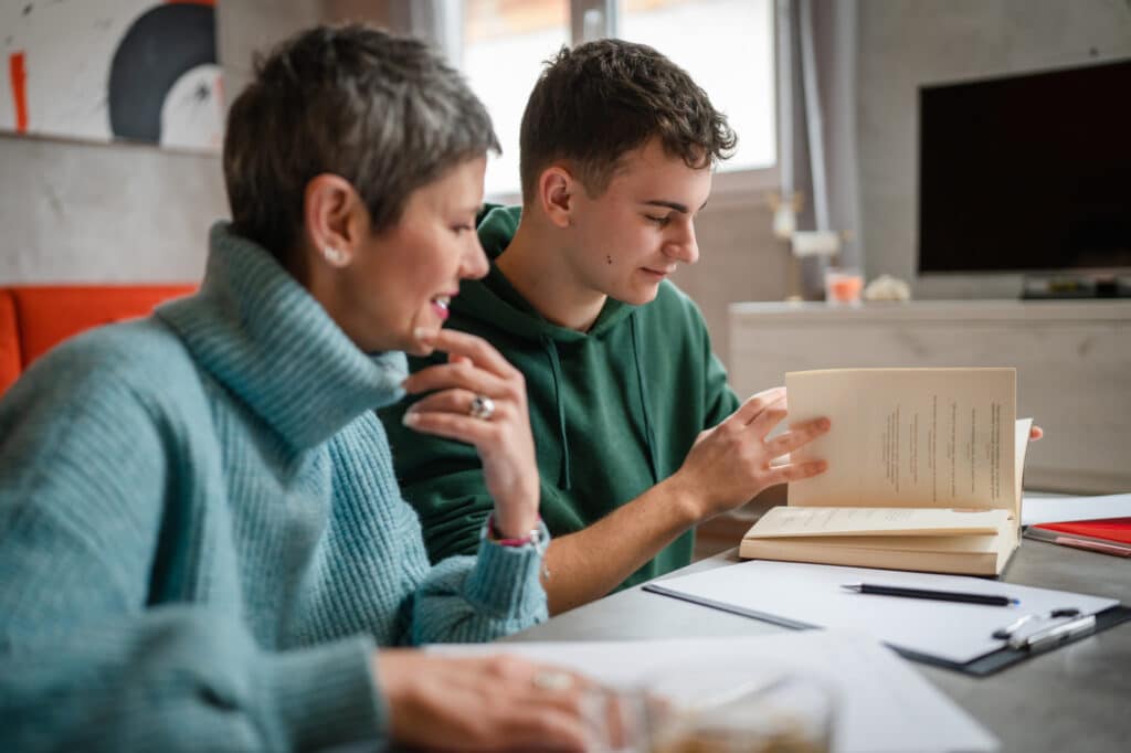 Un étudiant adolescent caucasien étudie avec l’aide de son tuteur, professeur ou de sa mère, une femme âgée, à la maison, lors d’une leçon particulière pour préparer un examen. Concept d’éducation, personnes réelles
